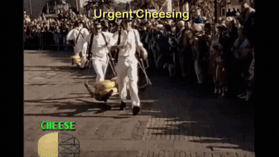 A Group Of Men Are Carrying A Bunch Of Cheese On A Cart While A Crowd Watches GIF