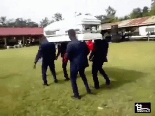 A Group Of Men Are Carrying A Coffin On Their Backs . GIF