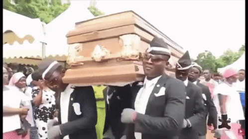 A Group Of Men Are Carrying A Coffin While Dancing . GIF