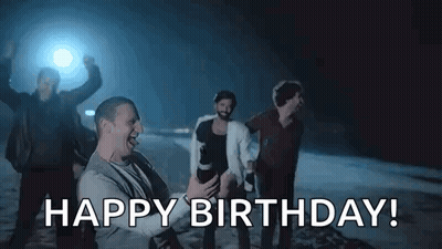 A Group Of Men Are Celebrating A Birthday With A Man Holding A Camera And Saying `` Happy Birthday '' . GIF