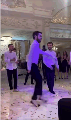 Men Dancing In Large Room With Purple Lights GIF
