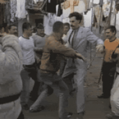 A Group Of Men Are Dancing In A Room With Clothes Hanging On A Rack GIF