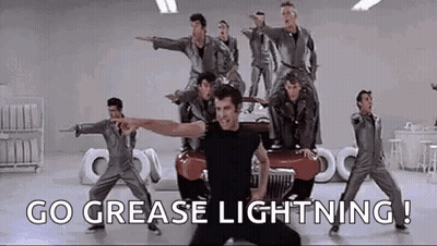 A Group Of Men Are Dancing In Front Of A Car With The Words `` Go Grease Lightning ! '' GIF