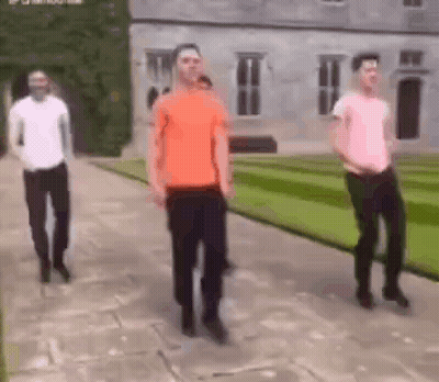 A Group Of Men Are Dancing In Front Of A Large Building . GIF