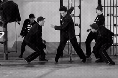 A Group Of Men Are Dancing In Front Of A Prison Cell With The Number 3 On It GIF