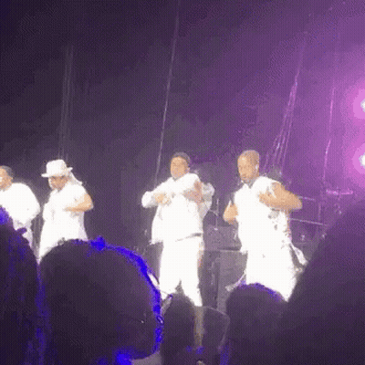 A Group Of Men Are Dancing On A Stage In Front Of A Crowd At A Concert . GIF