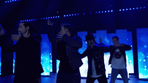 A Group Of Men Are Dancing On A Stage In Front Of Blue Lights GIF