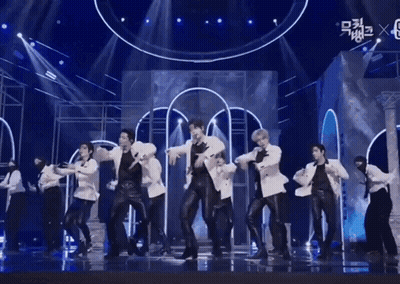 A Group Of Men Are Dancing On A Stage With A Blue Background . GIF