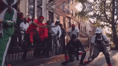 A Group Of Men Are Dancing On The Sidewalk In Front Of A Building . GIF