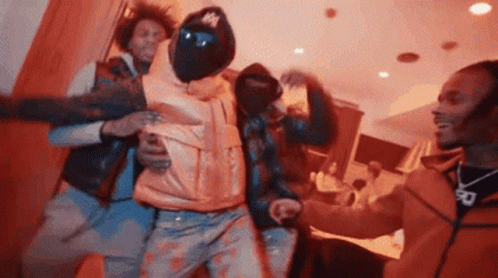 A Group Of Men Are Dancing Together In A Room . One Of The Men Is Wearing A Mask . GIF