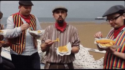 A Group Of Men Are Eating French Fries On A Bench GIF