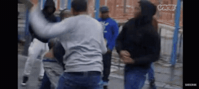 A Group Of Men Are Fighting On A Street In A Video . GIF