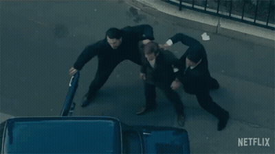 A Group Of Men Are Fighting On A Street With A Netflix Logo In The Background GIF