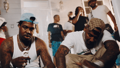 A Group Of Men Are Gathered In A Room And One Of Them Is Wearing A Hat That Says Gucci GIF