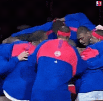 A Group Of Men Are Huddled Together In A Huddle . GIF