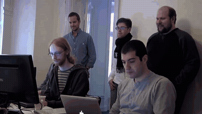 A Group Of Men Are Looking At A Laptop With An Apple Logo GIF
