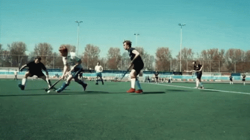 A Group Of Men Are Playing A Game Of Field Hockey On A Field GIF