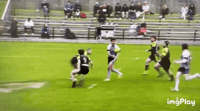 A Group Of Men Are Playing A Game Of Rugby On A Field With Bleachers In The Background . GIF