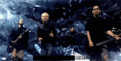 A Group Of Men Are Playing Guitars And Singing In Front Of A Screen That Says " Real " GIF