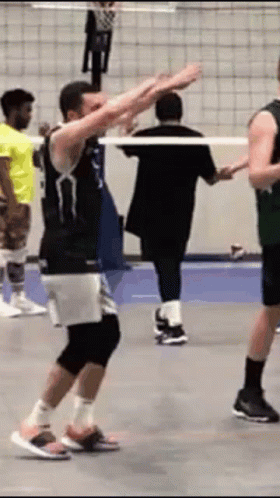 A Group Of Men Are Playing Volleyball On A Court And One Of Them Is Dancing . GIF