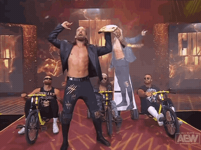 A Group Of Men Are Riding Bikes On A Stage That Says Aew On It GIF