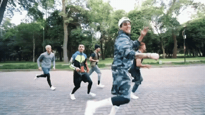 A Group Of Men Are Running On A Brick Road In A Park GIF