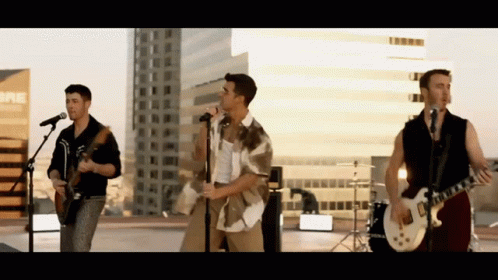 A Group Of Men Are Singing And Playing Guitars In Front Of A Sign That Says Bre GIF