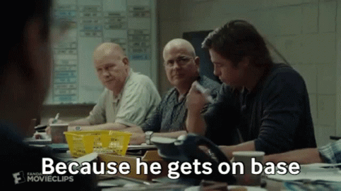 A Group Of Men Are Sitting Around A Table And One Of Them Is Saying Because He Gets On Base . GIF