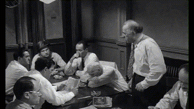 A Group Of Men Are Sitting Around A Table And Talking GIF