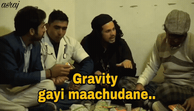 A Group Of Men Are Sitting Around A Table With A Caption That Says Gravity Gayi Maachudane GIF