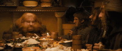 A Group Of Men Are Sitting Around A Table With Food And Drinks GIF