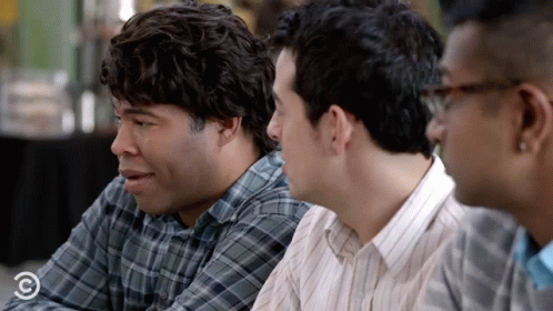 A Group Of Men Are Sitting At A Table And One Of Them Is Wearing A Plaid Shirt That Says Comedy Central On It GIF