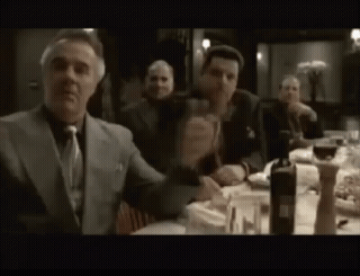 A Group Of Men Are Sitting At A Table Drinking Wine And Eating Food . GIF
