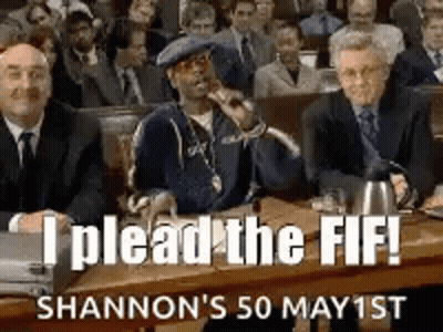 A Group Of Men Are Sitting At A Table In A Courtroom And A Man Is Holding A Microphone . GIF
