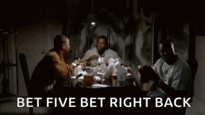 A Group Of Men Are Sitting At A Table In A Dark Room Talking . GIF