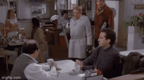 A Group Of Men Are Sitting At A Table In A Restaurant And Talking To Each Other . GIF