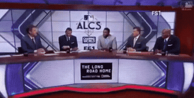 A Group Of Men Are Sitting At A Table In Front Of A Large Screen That Says Alcs GIF