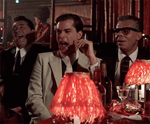 A Group Of Men Are Sitting At A Table With A Red Lamp GIF
