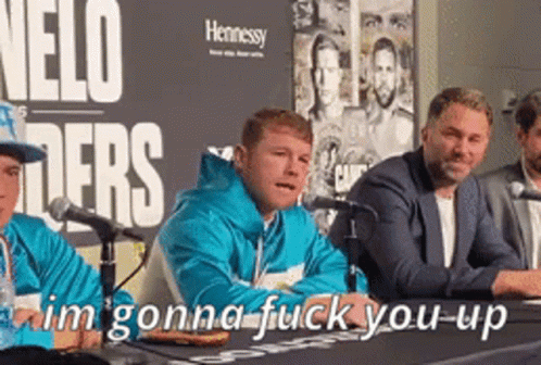 A Group Of Men Are Sitting At A Table With Microphones In Front Of A Sign That Says Nelo Fighters GIF