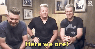 A Group Of Men Are Sitting In A Room With The Words Here We Are . GIF