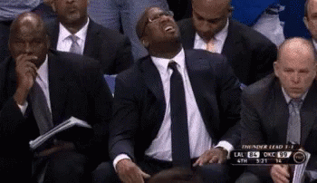 A Group Of Men Are Sitting In A Stadium Watching A Basketball Game . GIF