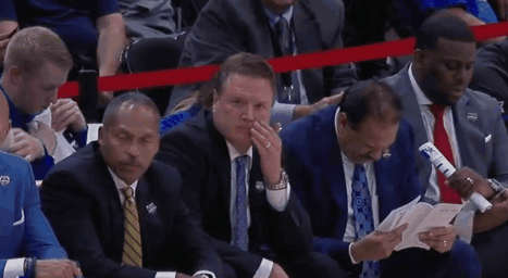 A Group Of Men Are Sitting In A Stadium Watching A Basketball Game GIF