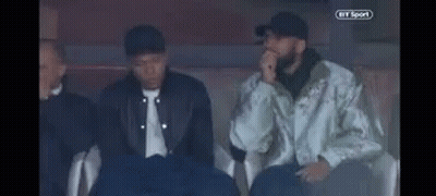 A Group Of Men Are Sitting In A Stadium Watching A Game . GIF