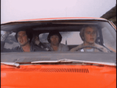 A Group Of Men Are Sitting In An Orange Car Looking Out The Window GIF