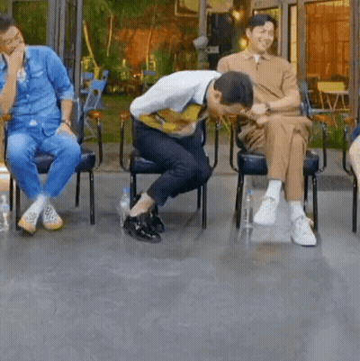 A Group Of Men Are Sitting In Chairs And One Of Them Is Kneeling Down . GIF