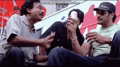 A Group Of Men Are Sitting In Front Of A Coca Cola Advertisement . GIF