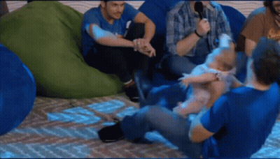 A Group Of Men Are Sitting On Bean Bag Chairs And One Of Them Is Holding A Baby . GIF