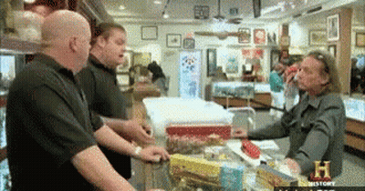 A Group Of Men Are Standing Around A Counter In A Store With A Sign That Says History On It GIF