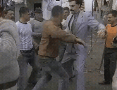 A Group Of Men Are Standing Around A Man In A Suit And Tie Standing In A Crowd . GIF