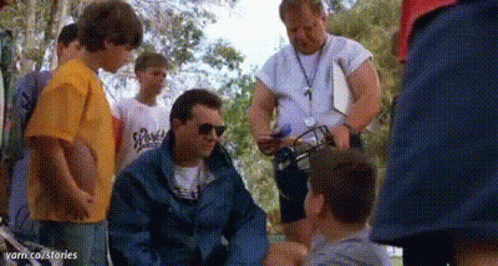 A Group Of Men Are Standing Around A Man Sitting On The Ground . GIF
